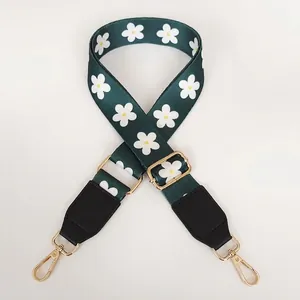 Detail of adjustable green shoulder strap with white daisy pattern and gold swivel hooks