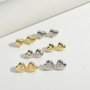Detailed flat lay of heart-shaped stud earrings in polished gold and silver finishes