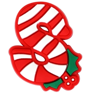 Macro detail of red and white candy cane shoe charm accessory with green holly leaves