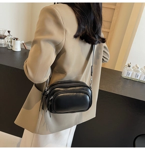 Detail of black multi-zipper leather crossbody bag with wide strap on a model