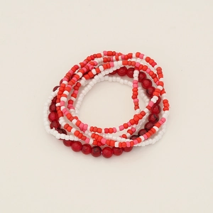Top-down view of multi-layered bead bracelet set in red, white and marble patterns