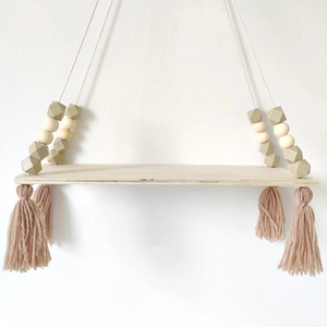 Detail of wooden wall shelf with macaron beads, light brown accents and pink cotton tassels