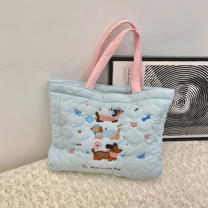 Detailed view of blue quilted cotton bag with cartoon embroidery on white faux fur carpet