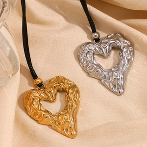 Close-up of gold and silver hammered texture heart pendants on silk fabric
