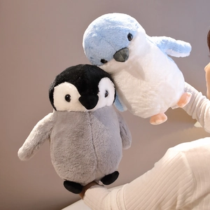 Close-up of soft plush penguin dolls in grey and blue held by hands for cozy feel