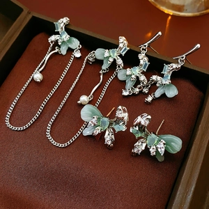 Detailed view of silver bow earrings with light green zircon tassels in a jewelry box