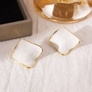 Detail of minimalist white enamel square stud earrings with gold plated irregular frame