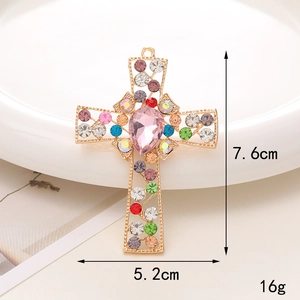 Macro detail of cross pendant with colorful rhinestones and pink drop stone, 7.6cm x 5.2cm