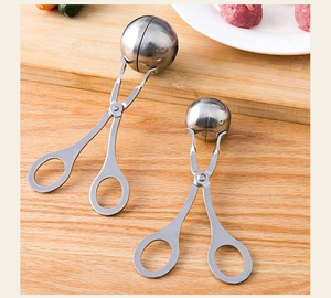 Detailed view of two different sizes of stainless steel meatball makers on a wooden board