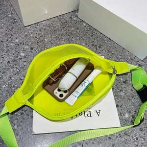 Top view of neon green transparent PVC chest bag showing internal items and strap buckle