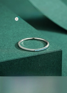 Vue macro d'une bague en argent S925 avec petites pierres turquoise sur fond vert