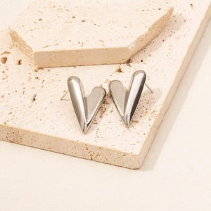 Macro shot of polished heart-shaped stainless steel stud earrings on natural stone