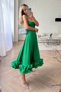 Detail of elegant bright green midi dress featuring a sculptural ruffled wave hemline