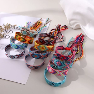 Handmade woven friendship bracelets with colorful geometric patterns on silk background