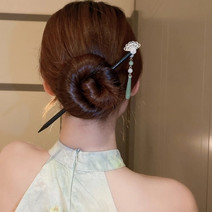 Detail view of flower hair stick with green tassel in a bun, Chinese style accessory