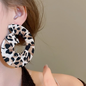 Detailed close-up of a model wearing leopard print fabric hoop earrings with retro design