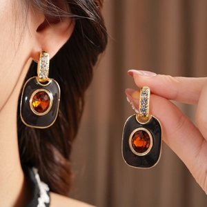 Close-up of vintage enamel square earrings with orange gemstones and gold finish