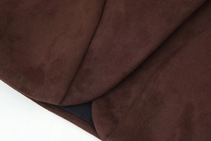 Detailed macro view of dark brown faux suede fabric with precise stitching on hem