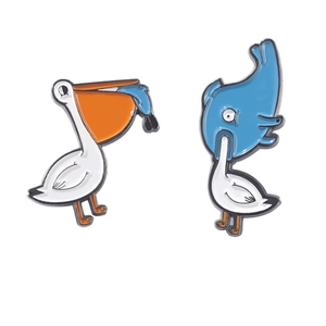 Whimsical enamel pins set featuring a white pelican and a blue whale in a mutual swallowing design