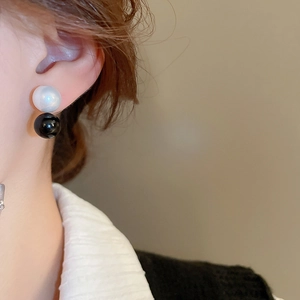 Detail showing minimalist double bead earrings with pearl white and black spheres on model