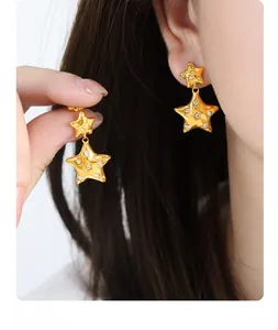 Close-up of gold star earrings with sparkling crystals worn by a model in detail