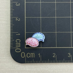 Macro view of mini resin heart and cloud charms with Love and Baby text on a scale mat
