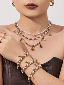 Close-up of stacked French pearl bead bracelets and bohemian gold necklaces on a model