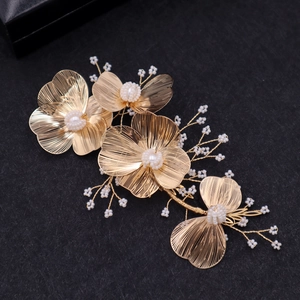 Golden flower bridal hairpiece with pearls and wire-woven floral details on black surface