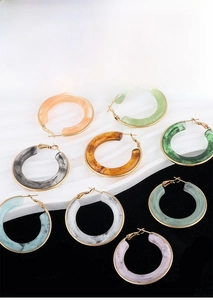 Detail of C-shaped marble resin earrings with gold stainless steel base in multiple colors