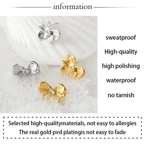 Detail of gold and silver bow stud earrings with PVD plating on white seashell