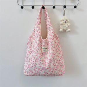 Close-up of pink floral quilted shoulder bag with brand woven label and plush lamb charm