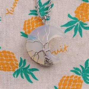 Macro detail of crescent moon opal pendant with silver Tree of Life wire wrapping