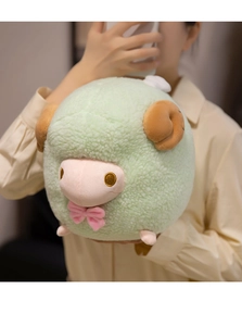 Detail of mint green plush lamb toy held by hands showing soft sherpa texture and bow