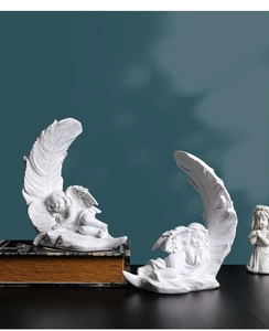 Detailed macro view of white resin angel sculptures resting on feathers for home decor