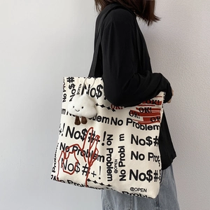 Dettaglio della borsa tote in tela bianco sporco con spalline nere e ciondolo nuvola