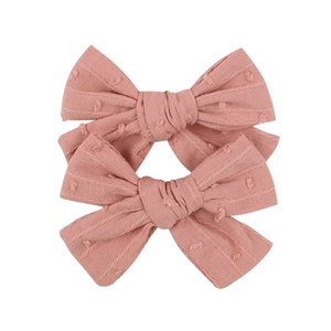 Detail of pink embroidered lace bow hair clips with polka dots and soft cotton texture