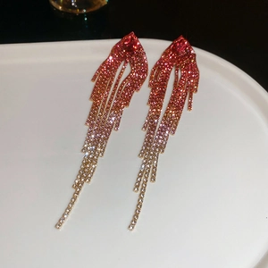 Macro shot of long fringe earrings featuring vibrant pink to gold rhinestone gradients