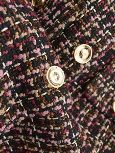 Close-up of multicolor tweed fabric with golden threads and round metal button detail