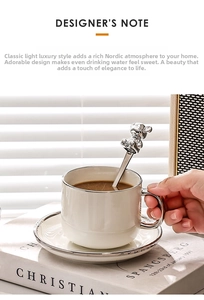 Close-up of luxury white ceramic coffee cup with silver trim and cute metal bear spoon