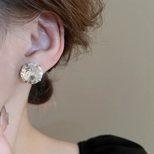 Close-up of elegant gold stud earrings with a large round cubic zirconia on a model