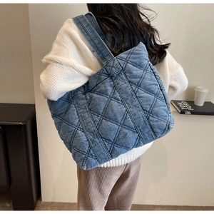 Détail du grand sac cabas en denim matelassé bleu avec surpiqûres losanges sur mannequin