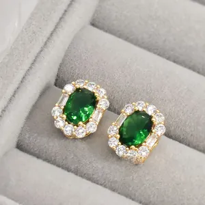 Detail of vintage emerald green stud earrings with cubic zirconia halo on gold base