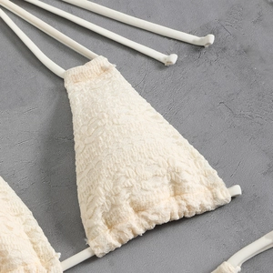 Macro detail of creamy lace crochet bikini top with wave edges and string ties