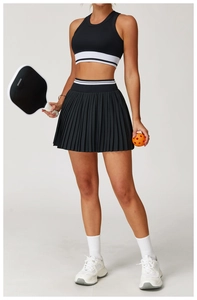 Detail of black seamless sports top with striped hem and pleated athletic skirt