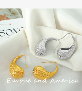 Macro detail of teardrop earrings with hammered texture in gold and silver finish