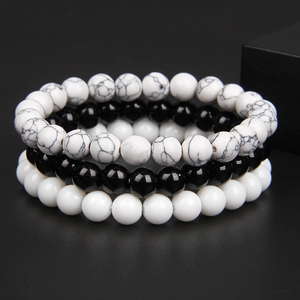 Detailed view of three 8mm natural stone bead bracelets in marble, black, and white colors
