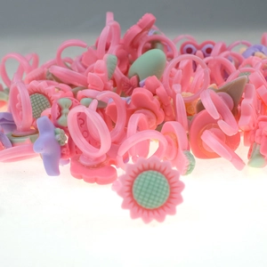 Close-up of pink plastic toy rings for girls with sunflower and ice cream shapes
