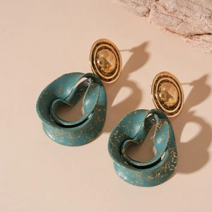 Detailed view of vintage gold earrings with textured dark green geometric pendants