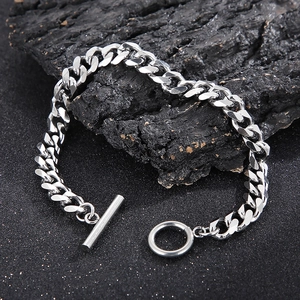 Macro detail of silver stainless steel Cuban link bracelet with OT toggle clasp on dark wood