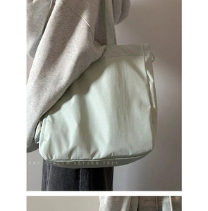Detailed side view of the large mint green nylon tote bag on a female shoulder